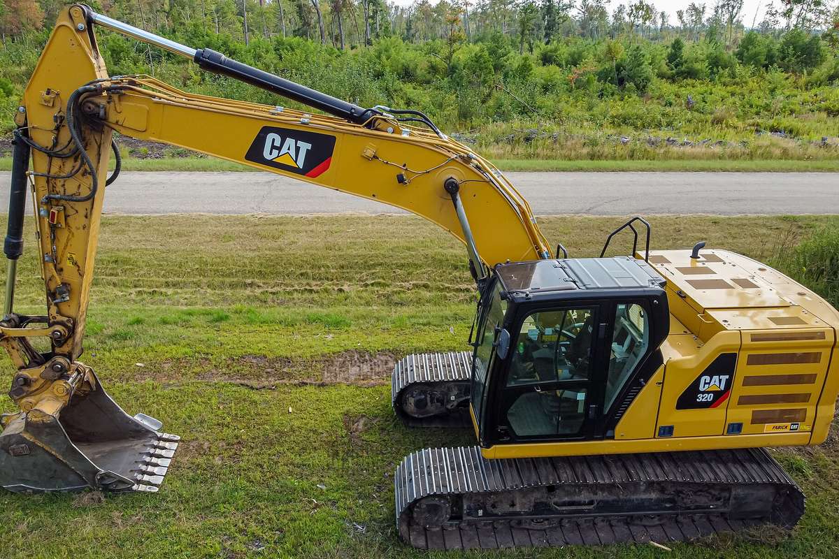 Excavadora hidráulica de orugas de unas 20 toneladas, vista de lado, estacionada sobre pasto